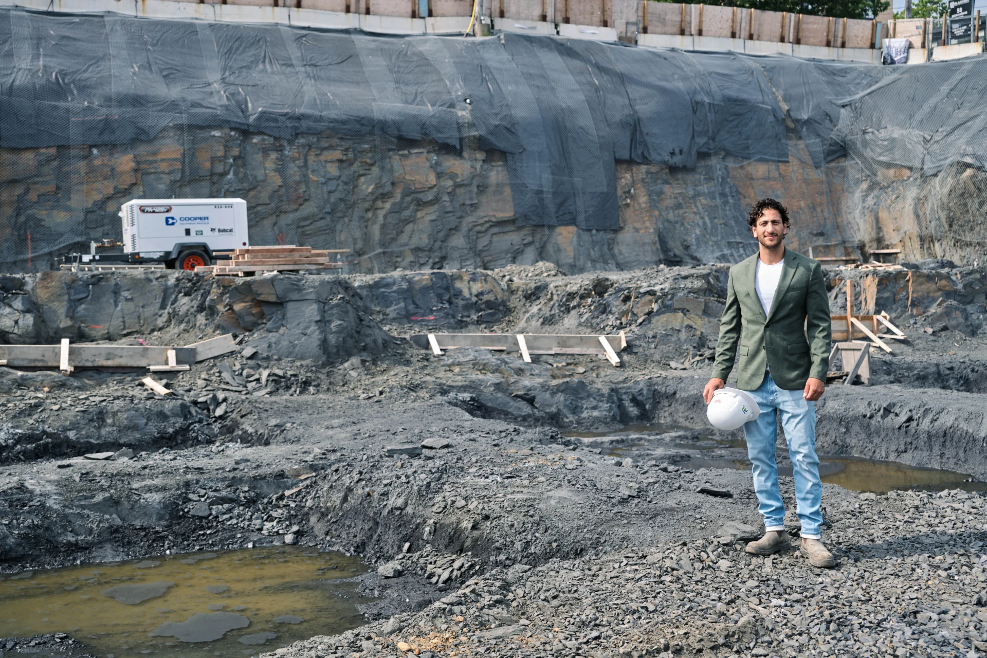 Neyaz Saberi standing at an active construction site in Halifax, holding a hard hat
